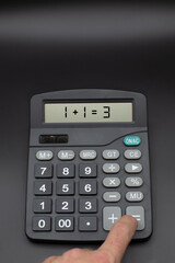 Calculator on office desk with incorrect calculation on black background, finger is pushing calculate button