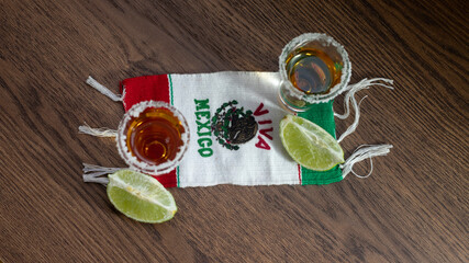 SHOTS OF TEQUILA ON VIVA MEXICO SCARF WITH LEMON AND SALT ON A RUSTIC WOODEN TABLE