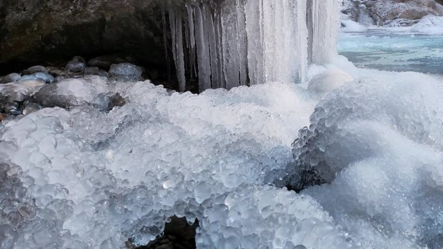 Ice formation from a frozen waterfall above a cave with white snow. Frozen waterfall. Cold and frost landscape. Tourism in Spain, Catalonia, Barcelona, Osona, Vidra, Salt del Moli.