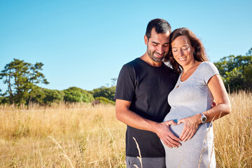 Happy latin future parents couple making heart shape with hands in belly, outdoors in nature