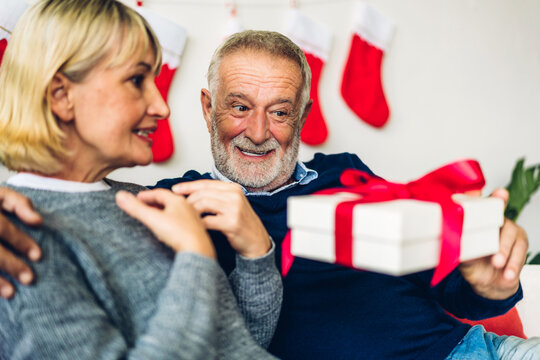 Romantic sweet senior couple having fun and smiling while celebrating enjoying valentine day time together.Senior man giving gift box surprise to wife in valentine day at home