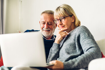 Senior couple reading documents and calculating bills to pay in living room at home.Retirement...