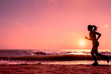 Fototapeta premium Silhouette slim sport female running on beach in sunset or sunrise