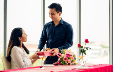 Young handsome man giving gift box surprise to girlfriend in valentine day