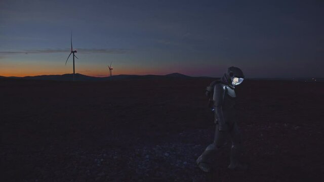 Wind station worker in robotic costumer walking on agriculture field examining technologies and electricity system. Artificial intelligence. New development. Cyborg.