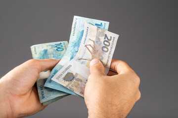 Hand of a man holding Brazilian notes Reais