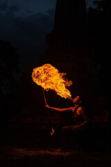 a fire artist blowing a large flame from her mouth ( a woman spits fire) in Thailand