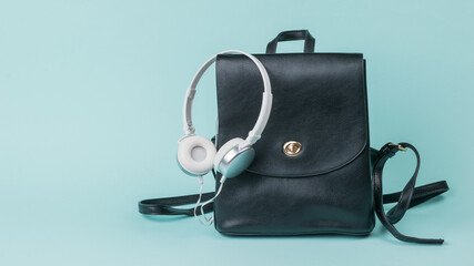 White headphones and a black leather backpack on a blue background.