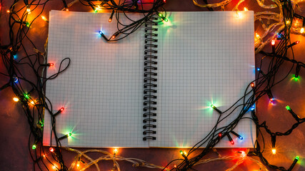 Notebook on a desk. Lights around. Love and devotion.
A notebook sits on the table, opened, ready to be filled with best wishes and love. Lights are twinkling around it. Write your Valentine's messag
