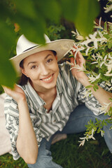 Woman in a spring park. Brunette in a hat. Girl near blossom tree.