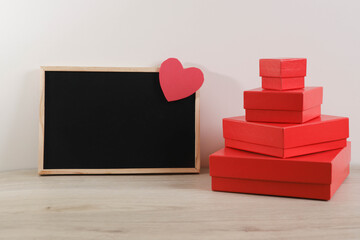Red gift boxes on the wall background with blackboard and heart