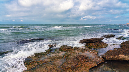 Fototapeta na wymiar Wave splashing at the rocks, freshness on beach
