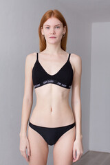 Fototapeta premium snap shot of pretty model in black lingerie on white background with red hair 