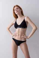 Fototapeta premium snap shot of pretty model in black lingerie on white background with red hair 