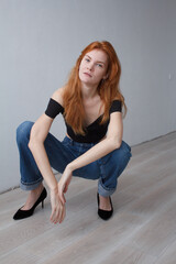 ginger woman wearing in top and jeans sitting on the floor