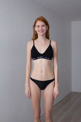 Fototapeta premium snap shot of pretty model in black lingerie on white background with red hair 