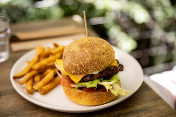 A delicious cheeseburger and fries served on an outside table