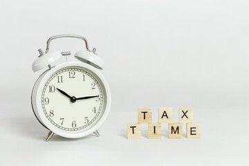 White alarm clock with tax wooden block cube on white background.