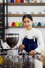Young asian woman in apron using Espresso Machine Portafilters to make fresh coffee drink. Professional barista preparing coffee on counter.
