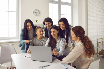 Team of happy smiling business women, gathered at laptop computer in office, meeting coworkers via...