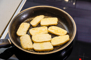 Halloumi cheese frying in a pan with olive oil.