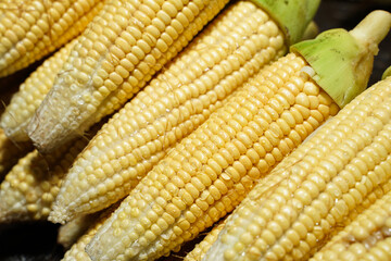 Pile of peeled corn ready to be used as a cooking ingredient. Peeled corn leaving the skin on top. Market stall with corn cobs. Sweet corn sale in fresh market. Fresh vegetables at traditional market.