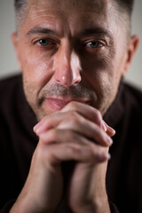 Fototapeta premium portrait of an adult man, hands folded together, looking at the camera.