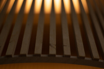 Luminaire made of wooden battens. The interior is in detail. Soft light on untreated wood. Consecutive boards are arranged in a row. Simple background.