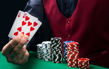 two playing cards in the hand of the dealer and chips, on the green cloth of the table in the casino