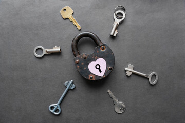 Obraz na płótnie Canvas Key to heart concept. Way to heart. Locked Heart with keyhole on old rusty lock and many keys around on dark black background