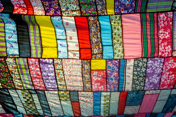 A huge colorful artistic fabric, made from a combination of colorful pieces of unused and collected clothes by a tailor.