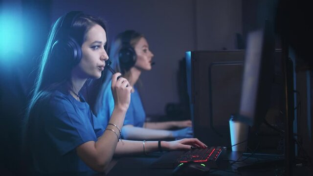 Two women playing an online game in the gaming club - a woman vaping on the foreground