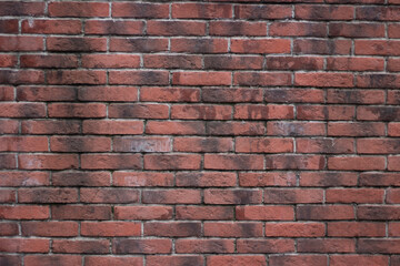 Naklejka premium Brick texture from old stone. 18th century brick wall. Old burnt brick masonry. Shooting details close-up. Aged red clay color. Rectangular blocks laid out in rows and held together with cement.
