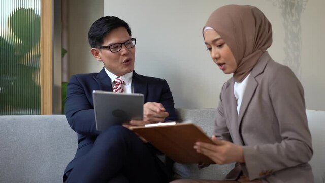Chinese business man talking on business with Muslim women. The Muslim secretary is reporting the market situation to the manager.