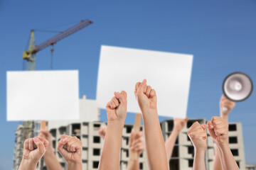 Hands of protesting people near unfinished building