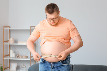 Overweight man with measuring tape at home. Weight loss concept