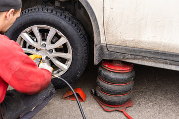 Naklejka premium Car mechanic removing wheel nuts to check brakes