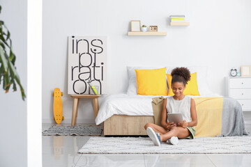 Teenage African-American girl with tablet computer at home