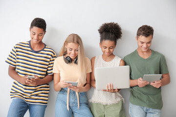 Teenagers with different devices on light background