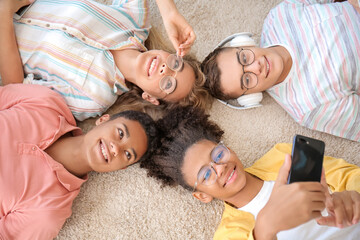 Teenagers taking selfie at home, top view