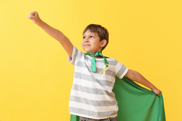 Little boy with golden ribbon wearing superhero costume on color background. Childhood cancer...