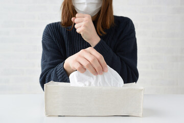 鼻水をかむためにティッシュをとる女性