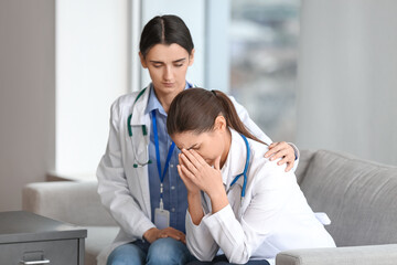 Female doctor calming her stressed colleague in clinic