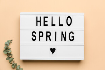 Board with text HELLO SPRING on color background