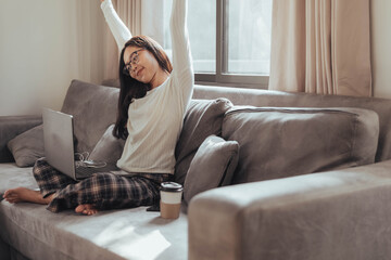 Young woman relaxing on sofa after working at home. Beautiful businesswoman resting and raising hands relax from work.