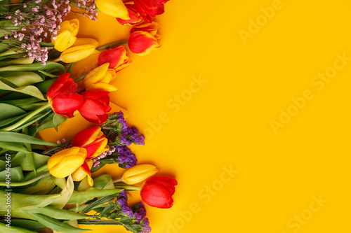 Yellow colorful Holiday banner. Bouquet of red yellow tulips on bright yellow background. Mother's day, Valentines Day, Birthday celebration concept. Hallo Spring, Copy space, top view, greeting card