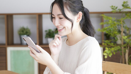 リビングでスマートフォンを見る若い女性
