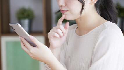 リビングでスマートフォンを見る若い女性