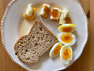Homemade Breakfast Plate with Cubed Mature French Tomme Cheese Slices, Boiled Half Cut Egg, Buttercream and Sourdough Bread.
