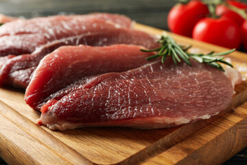 Board with fresh raw steak meat on wooden background